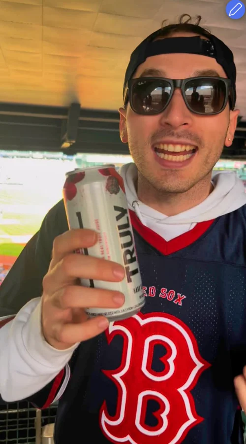 A fan in the stands holding a hard seltzer